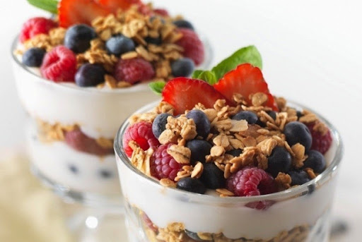 Bol de yaourt nature avec granola et fruits rouges